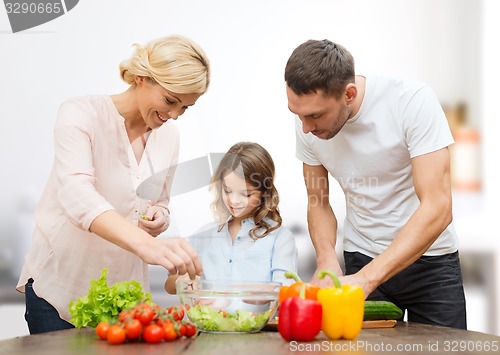 Image of happy family cooking vegetable salad for dinner