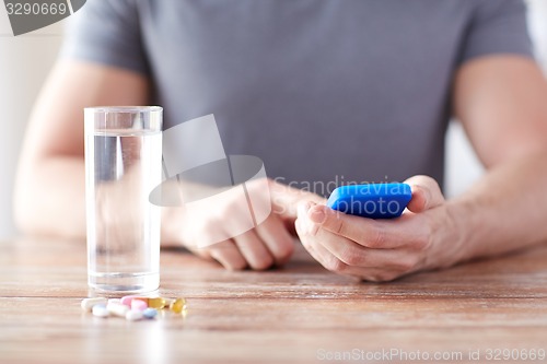 Image of close up of hands with smartphone, pills and water