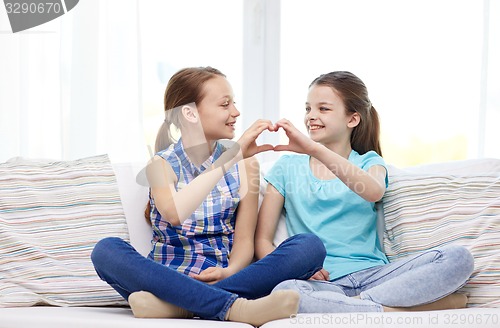 Image of happy little girls showing heart shape hand sign