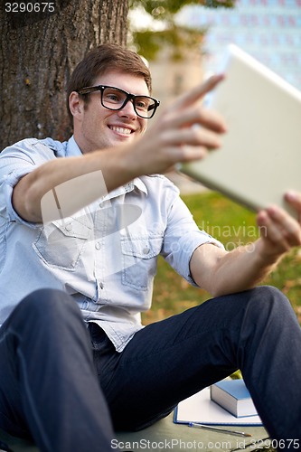 Image of happy teenage boy with tablet pc taking selfie