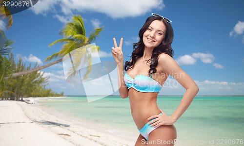 Image of happy woman in swimsuit showing victory hand sign