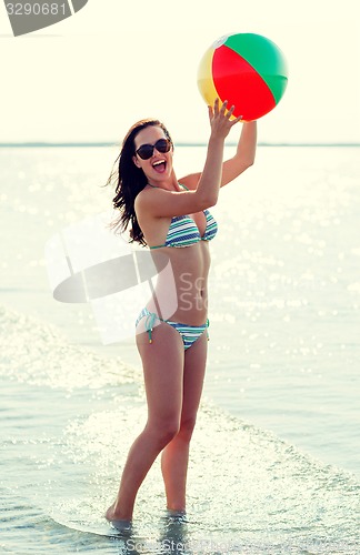 Image of smiling teen girl in sunglasses with ball on beach