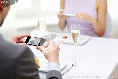 Image of close up of couple with smartphones at restaurant