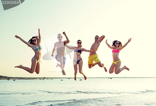 Image of smiling friends in sunglasses on summer beach