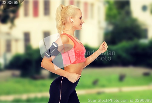 Image of sporty woman running with smartphone and earphones