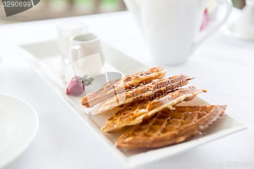 Image of close up of waffles on plate at breakfast table 