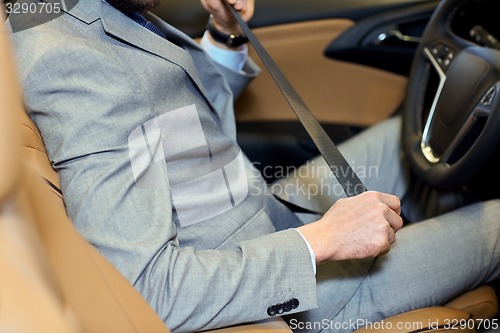 Image of close up of man fastening seat safety belt in car