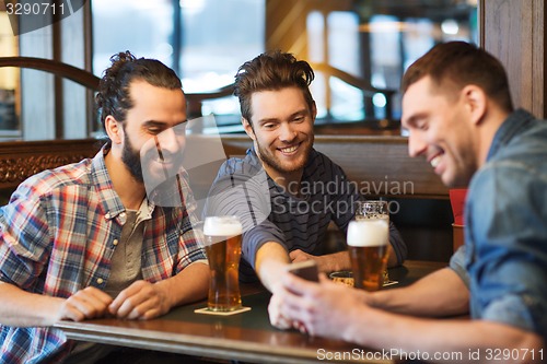 Image of male friends with smartphone drinking beer at bar