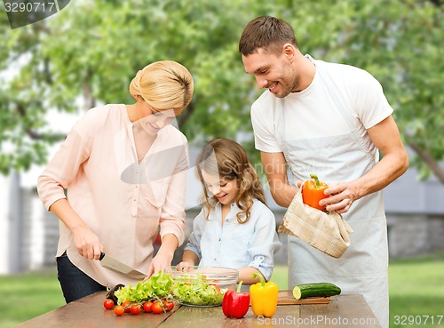 Image of happy family cooking vegetable salad for dinner