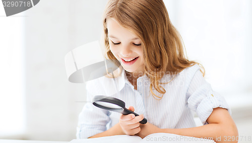 Image of girl reading book with magnifier at school