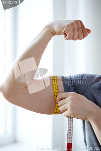 Image of close up of male hands with tape measuring bicep