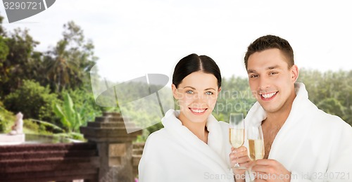 Image of happy couple in bathrobes with champagne at resort