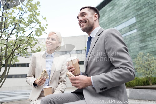 Image of smiling businessmen with paper cups outdoors