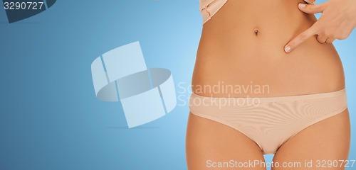 Image of close up of woman pointing finger at her abs