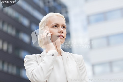 Image of serious businesswoman with smartphone outdoors