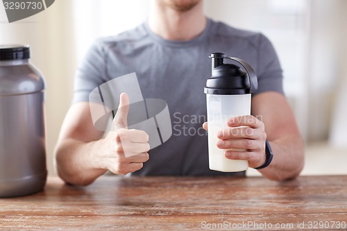 Image of man with protein shake bottle showing thumbs up