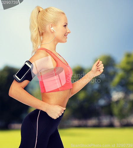 Image of sporty woman running with smartphone and earphones