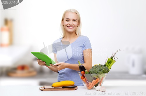 Image of smiling woman with tablet pc cooking vegetables 