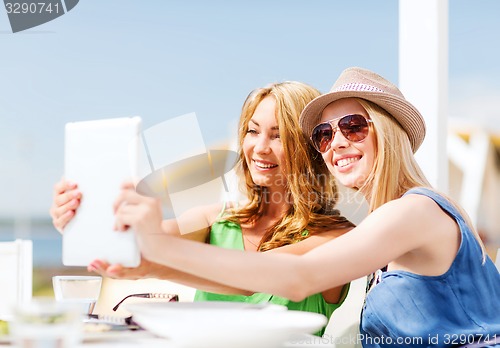 Image of girls taking photo in cafe on the beach