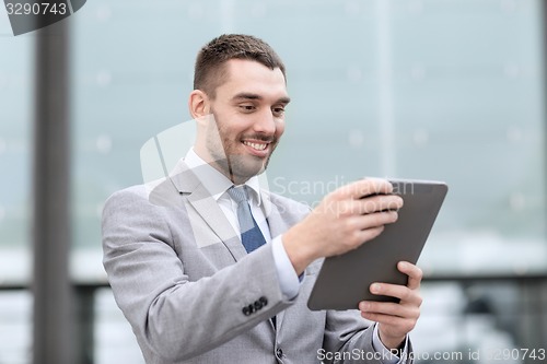 Image of smiling businessman with tablet pc outdoors