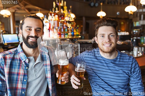 Image of happy male friends drinking beer at bar or pub