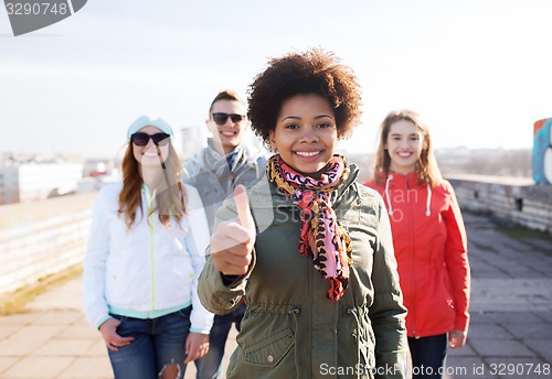 Image of happy teenage friends showing thumbs up on street