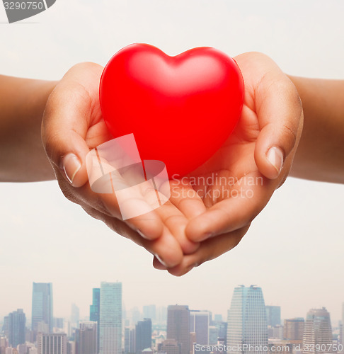 Image of close up of female hands holding small red heart