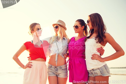 Image of group of smiling women in sunglasses on beach