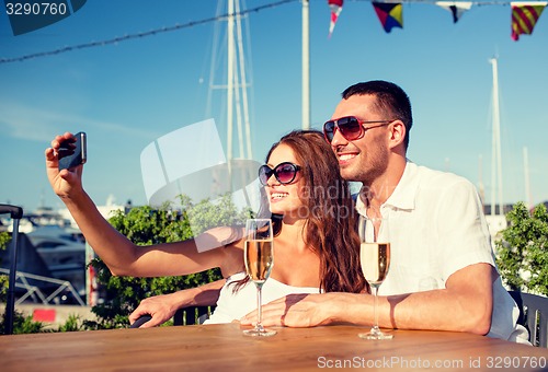 Image of smiling couple drinking champagne at cafe