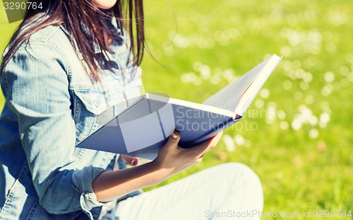 Image of close up of smiling young girl with book in park