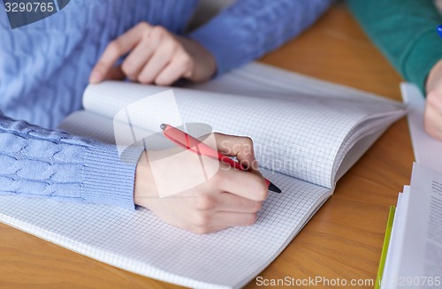 Image of close up of student hands writing to notebook