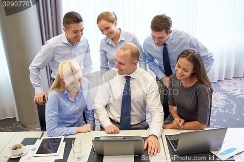 Image of smiling business people with laptop in office