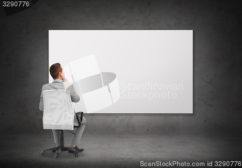 Image of businessman in office chair over white board