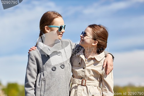 Image of happy little girls hugging and talking outdoors