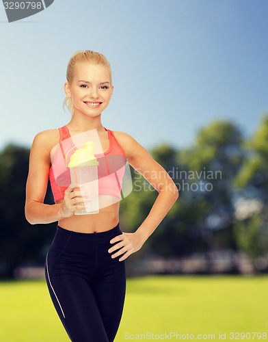 Image of smiling sporty woman with protein shake bottle