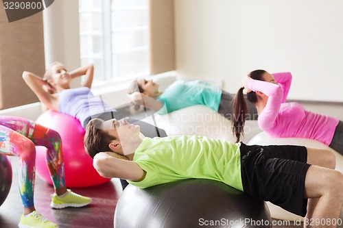 Image of happy people flexing abdominal muscles on fitball