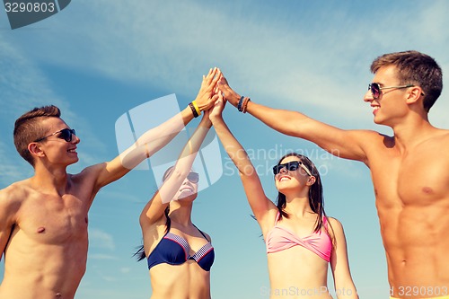 Image of smiling friends in sunglasses on summer beach