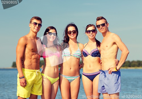 Image of smiling friends in sunglasses on summer beach