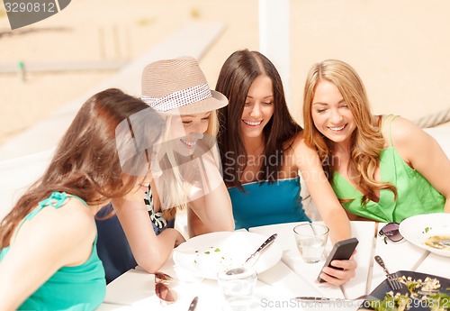 Image of girls looking at smartphone in cafe on the beach