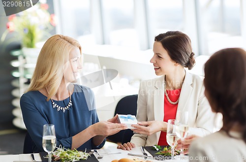 Image of happy women giving birthday present at restaurant