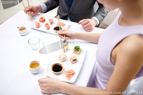 Image of close up of couple eating sushi at restaurant