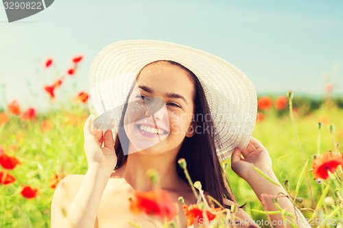 Image of smiling young woman in straw hat on poppy field