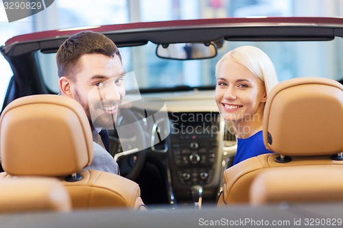 Image of happy couple sitting in car at auto show or salon