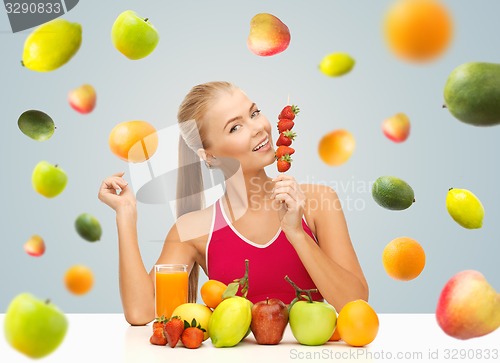 Image of woman with juice and fruits eating strawberries