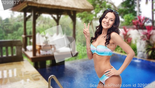 Image of happy woman in swimsuit showing victory hand sign