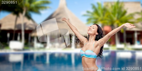 Image of happy woman in swimsuit with raised hands on beach