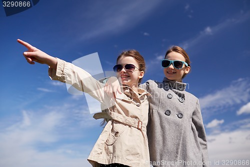 Image of happy little girls hugging and pointing finger