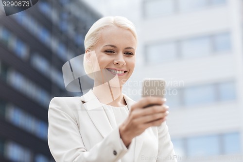 Image of smiling businesswoman with smartphone outdoors