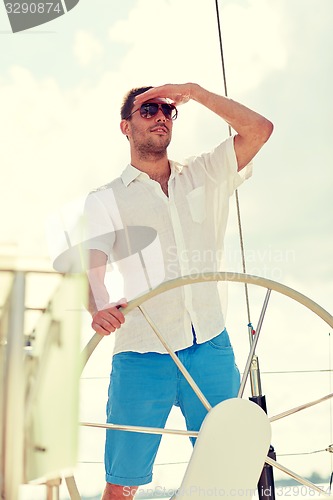 Image of young man in sunglasses steering wheel on yacht