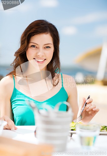 Image of girl eating in cafe on the beach